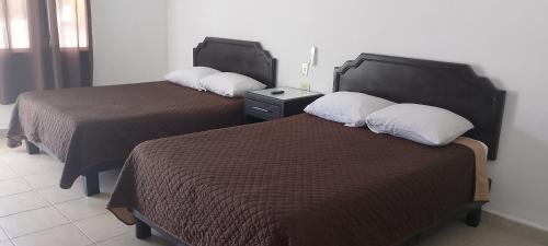 two beds sitting next to each other in a room at Hotel Estrella in Matamoros