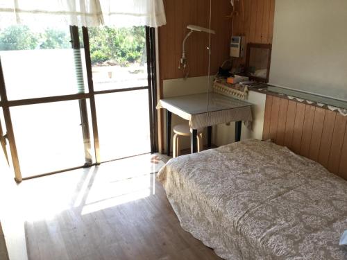 a bedroom with a bed and a desk and a window at Minshuku Zabaru in Ishigaki Island