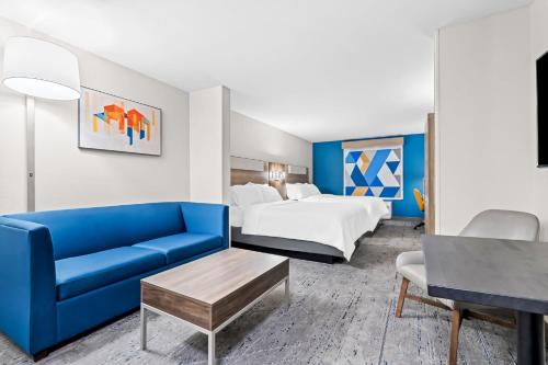 a hotel room with a bed and a blue couch at Holiday Inn Express Washington Court House by IHG in Washington Court House