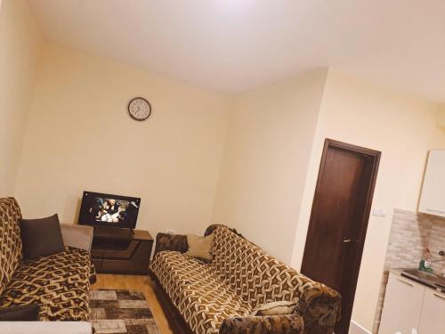 una sala de estar con 2 sofás y un reloj en la pared en Prestige 4, en Podgorica