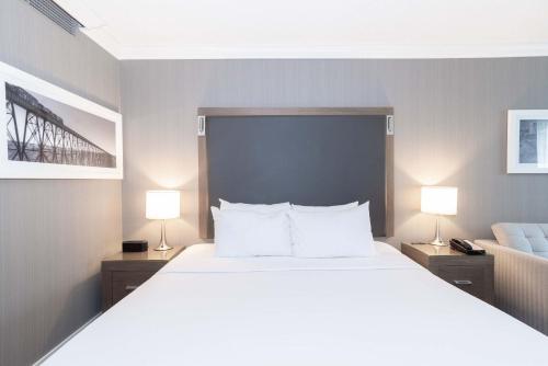 a bedroom with a large white bed with two lamps at Sandman Signature Lethbridge Lodge in Lethbridge
