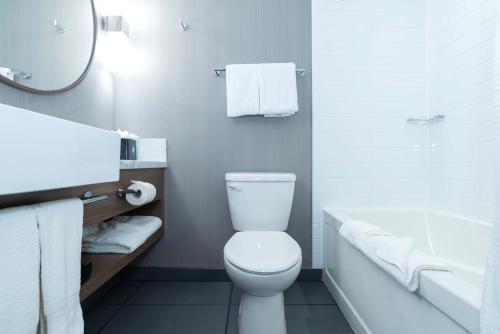 a bathroom with a toilet and a tub and a sink at Sandman Signature Lethbridge Lodge in Lethbridge