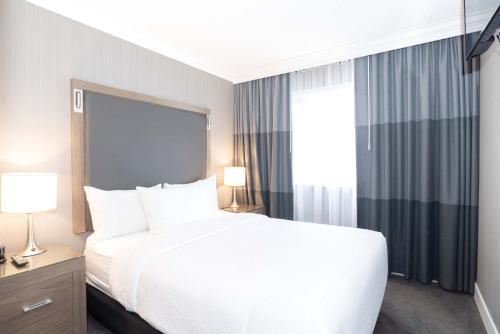 a bedroom with a large white bed and a window at Sandman Signature Lethbridge Lodge in Lethbridge
