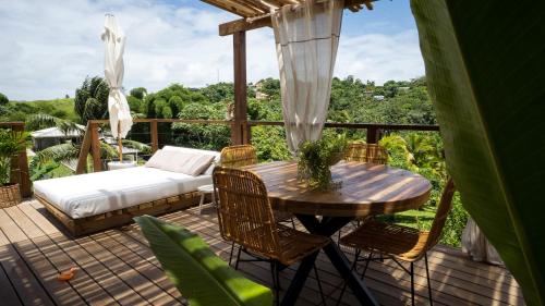 a wooden deck with a bed and a table and chairs at Mini Villa ATIKA Luxe Tropical pour Deux in Ducos