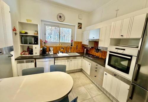 une cuisine avec des armoires blanches et une table à l'intérieur dans l'établissement Villa CAP AZUR BORD DE MER, à Roquebrune-Cap-Martin