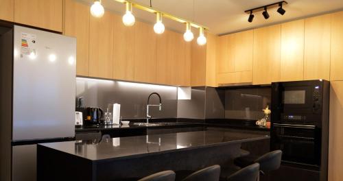 une cuisine avec un comptoir noir et des placards en bois dans l'établissement Hermoso Depto Nuevo 3D 2B y Litera Vista al Lago con Piscina Temperada , Jacuzzi, à Puerto Varas