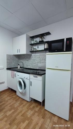 a kitchen with a washing machine and a refrigerator at Estudio Santa Catarina in Málaga