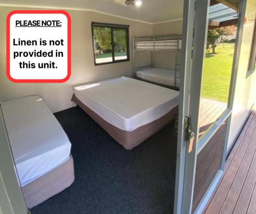 a room with two beds and a door with a sign at Sapphire Springs Holiday Park and Thermal Pools in Katikati