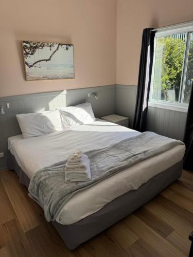 a bedroom with a bed with white sheets and a window at South Coast Retreat in Greenwell Point