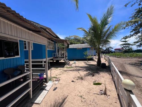 a blue house with a palm tree next to it at Khafii Village in Kampong Pasir Panjang