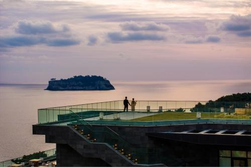 a man standing on top of a building overlooking the water at JW Marriott Jeju Resort & Spa in Seogwipo