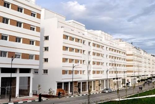 een groot wit gebouw aan een stadsstraat bij Le Joyau du Parc Tanger Vue Panoramique Parking Gratuit in Tanger