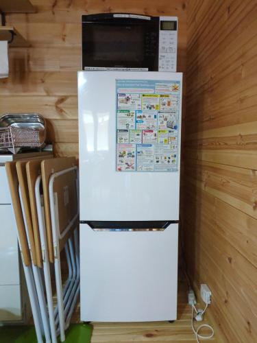 a white refrigerator with a microwave on top of it at Eco-friendly Log Cottage - be with nature in Furano