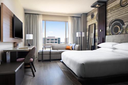 a hotel room with a bed and a desk and a couch at Dallas/Plano Marriott at Legacy Town Center in Plano
