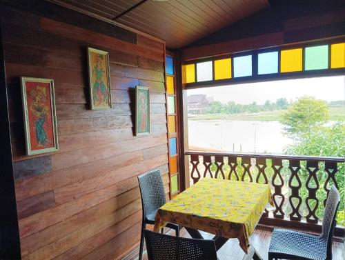a dining room with a table and chairs on a balcony at Hidden Holiday House in Ban Don Faek