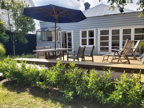 a patio with a table and chairs and an umbrella at Grafton House Villa Oasis, Central Auckland in Auckland