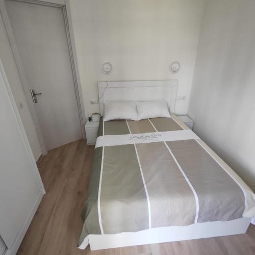 a white bed in a small room with a wooden floor at Moriya in Batumi