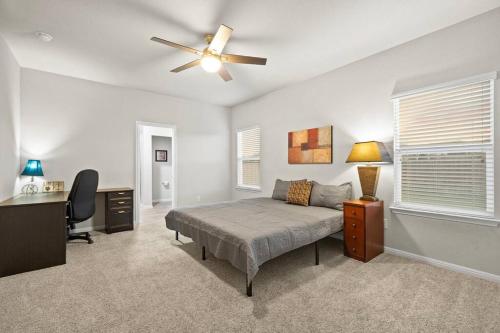 a bedroom with a bed and a desk and a ceiling fan at Elegant Home with Cozy Vibes in Pflugerville