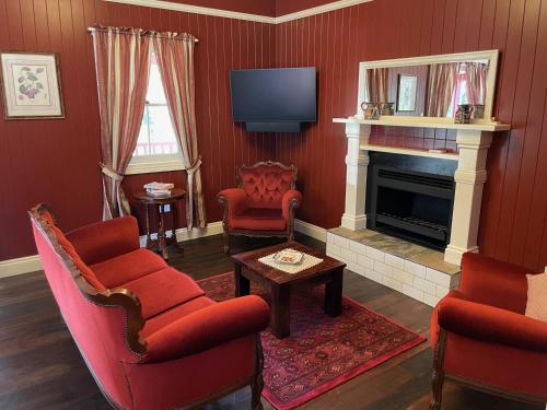 a living room with red chairs and a fireplace at Dusty Hill Vineyard - Moffatdale in Moffatdale