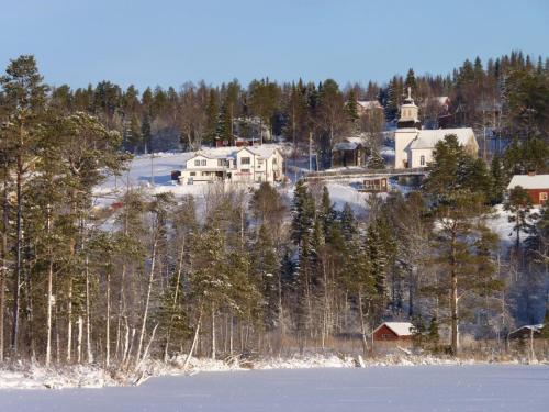 a house on top of a hill next to a lake at Borgvattnets B&B en Budget Hotel in Borgvattnet