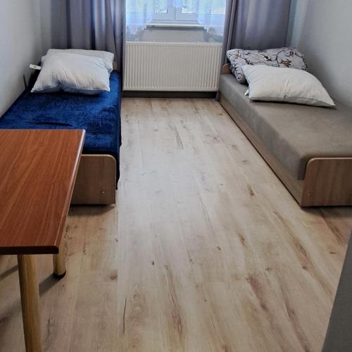 two beds in a room with a wooden floor at Zajazd Izabell in Świdry Dobrzyce