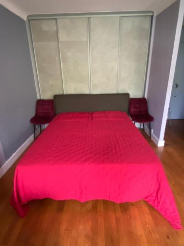 une chambre avec un lit rose avec deux chaises rouges dans l'établissement One Room Apartment in Paris Montmartre, à Paris