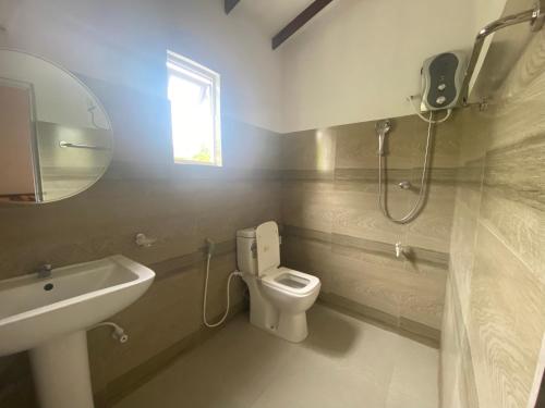 a bathroom with a toilet and a sink and a mirror at Serendib Villa in Negombo