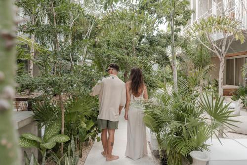 a bride and groom walking through a garden at Jungle Chic in Tulum