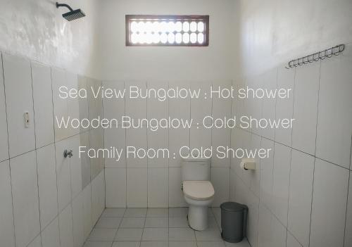 a white bathroom with a toilet and a window at Nusa Indah Bungalows in Gili Air