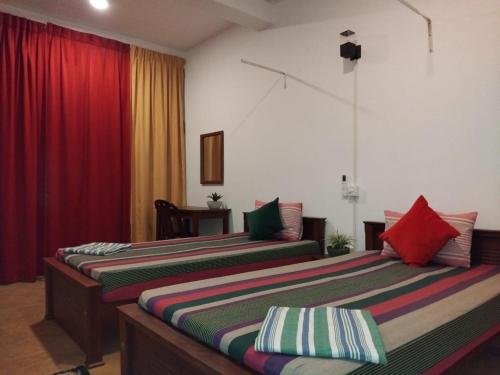 2 Betten in einem Zimmer mit roten Vorhängen in der Unterkunft Rusara Guest Home in Weligama