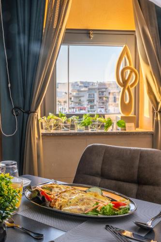 a plate of food on a table with a window at Casa Rosanna Malta B&B Adults only 16 plus in Marsaskala