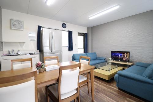 a kitchen and living room with a table and a blue couch at Ideal Yuuhigaoka イデアール夕陽丘 in Osaka