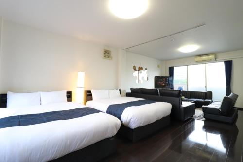 a hotel room with two beds and a couch at Ideal Yuuhigaoka イデアール夕陽丘 in Osaka