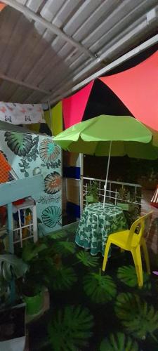 a table with a green umbrella and a yellow chair at MANOA "Lugar de descanso" HABITACION CON VISTA A LA CIUDAD, FRESCO Y VENTILADO in Ibagué