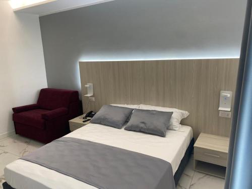 a bedroom with a bed and a red chair at Hotel Cocceio in Bacoli