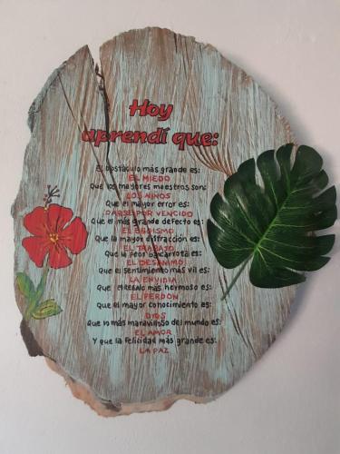 a sign on a wall with a flower and a leaf at MANOA "Lugar de descanso" HABITACION CON VISTA A LA CIUDAD, FRESCO Y VENTILADO in Ibagué