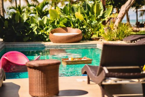 ein Pool mit Stühlen und Körben in einem Ferienresort in der Unterkunft Pousada Villa Tainá - Arraial d'Ajuda, Bahia in Arraial d'Ajuda