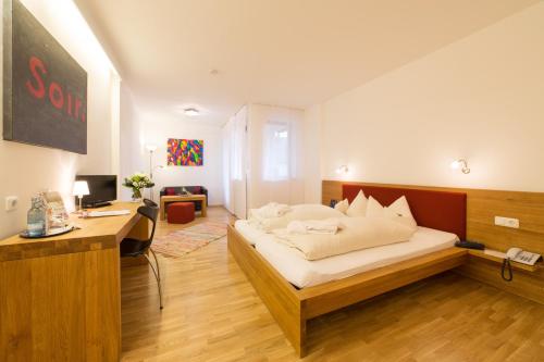 a bedroom with a bed and a desk in it at Hotel Bayernwinkel - Yoga & Ayurveda in Bad Wörishofen