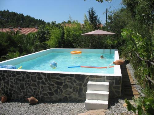 a swimming pool with a stone wall and an umbrella at Monte da Gravita in Ribeira do Salto