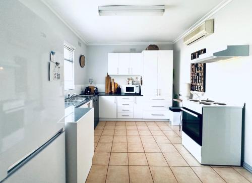 a kitchen with white cabinets and a tile floor at Treehouse Hideouts - Ground Level - Heygarth House Townhouse - Port of Echuca in Echuca