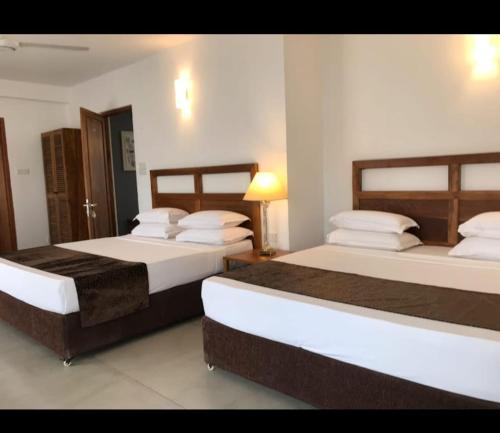 two beds in a hotel room with two bedsskirts at Manthila Resort Rajarata in Anuradhapura