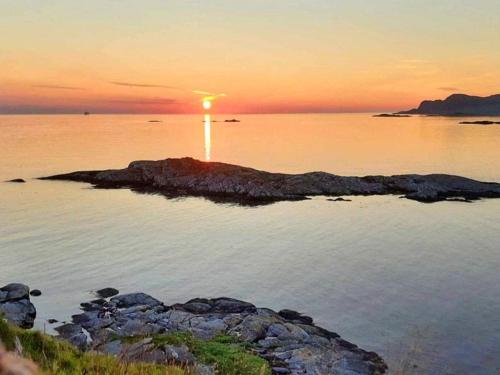 a sunset over a body of water with a lighthouse at 9 person holiday home in Åram in Sandvik