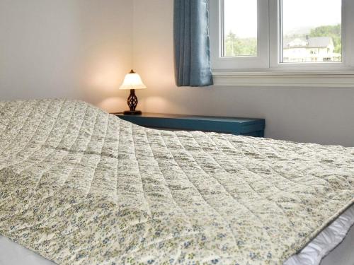 a bedroom with a bed and a lamp and a window at 9 person holiday home in Åram in Sandvik