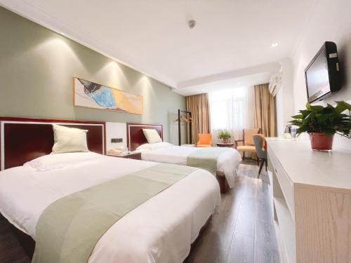 a hotel room with two beds and a television at 无锡东方枫韵商务酒店惠山万达店 in Mazhen