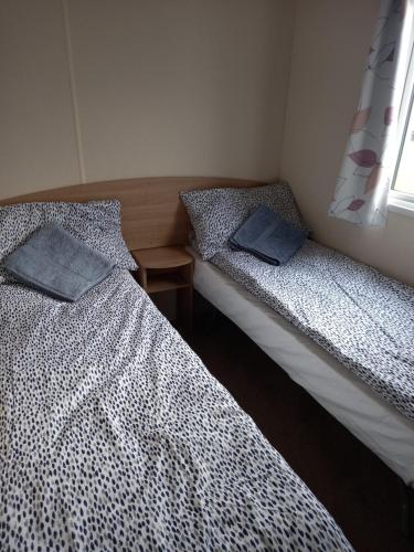 Dos camas individuales en una habitación con ventana. en Seton Sands Haven Park Moonstone Caravan, en Port Seton