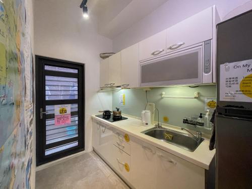 a small kitchen with white cabinets and a sink at On My Way Taitung Hostel in Taitung City
