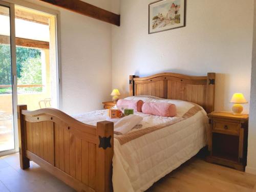 - une chambre avec un grand lit en bois et des oreillers roses dans l'établissement 105m2, piscine, 5 min des golfs, proche centre, à Saint-Raphaël