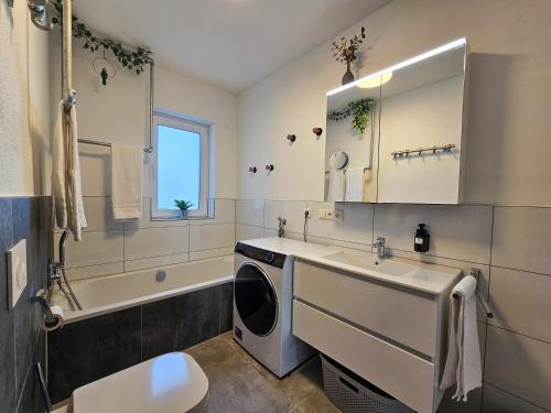 a bathroom with a sink and a washing machine at BETTER l industriaI apartment l Heimkino in Altusried