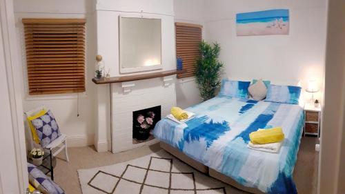 a bedroom with a blue bed and a fireplace at Homely Beachfront Apartment with Direct Beach Access - The Coachhouse in Narrabeen