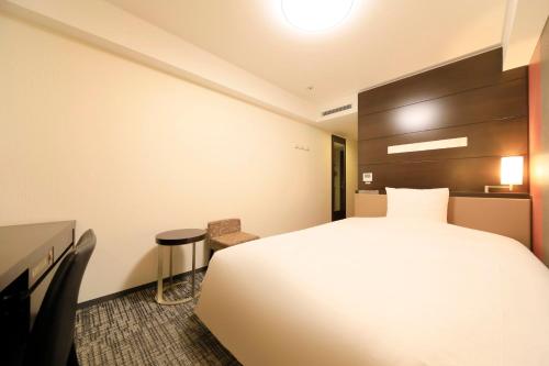 a hotel room with a large white bed and a stool at Richmond Hotel Premier Sendai Ekimae in Sendai